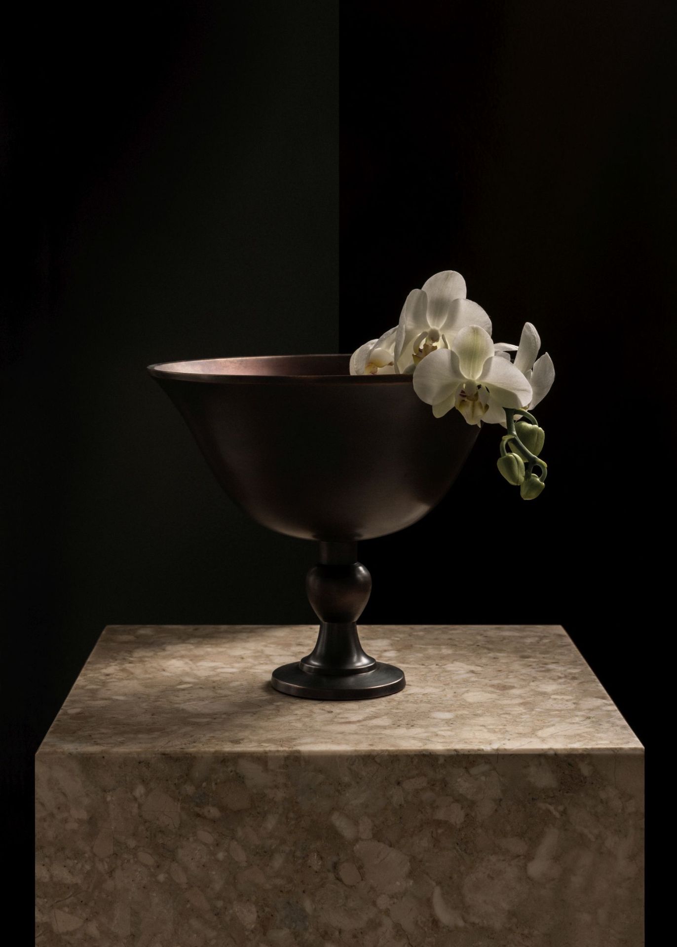 Pavot Schale von Audo Copenhagen aus dunklem Metall mit weißen Orchideen auf Marmortisch.