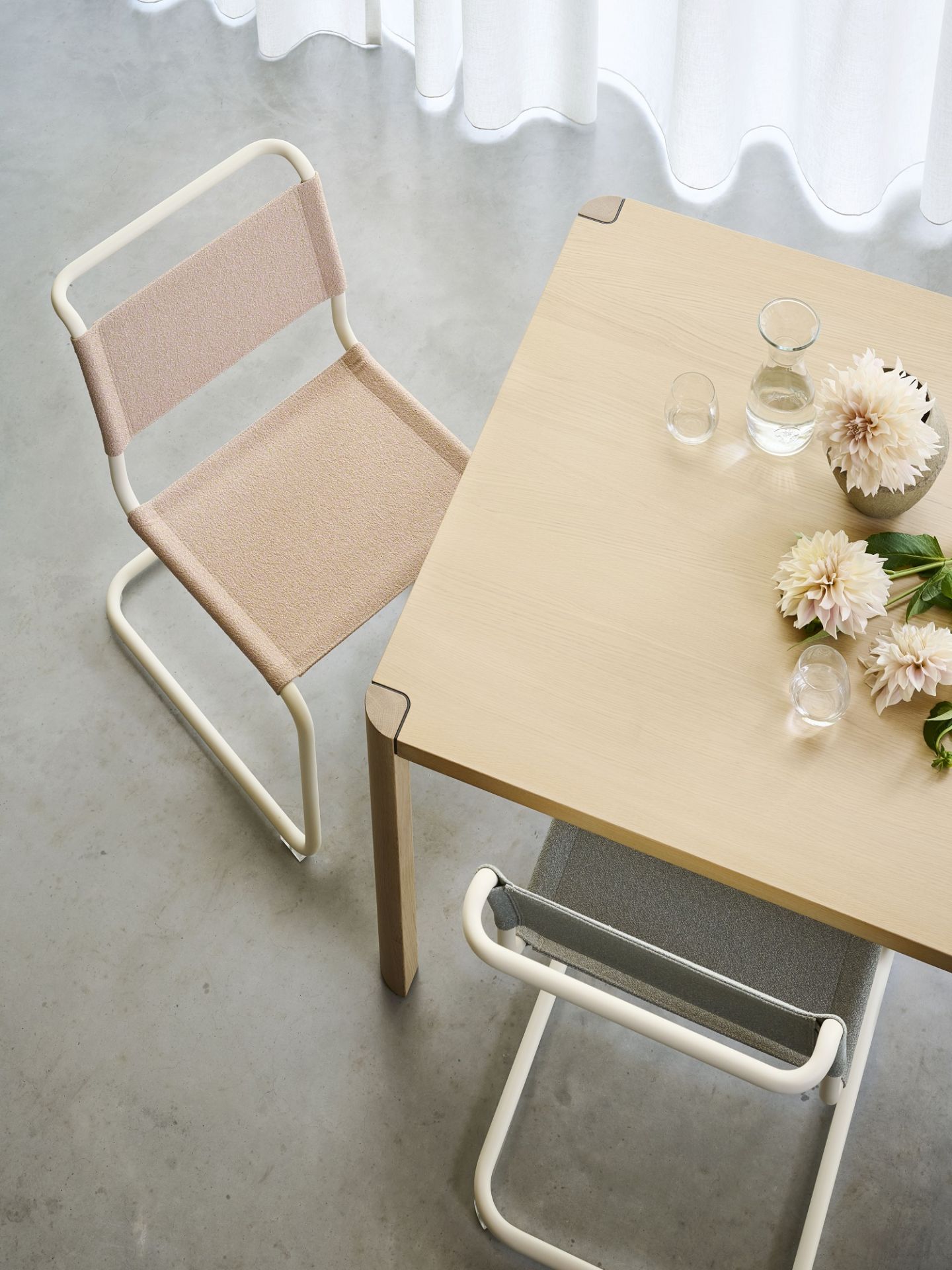 S 33 Freischwinger Stühle von Thonet in Beige und Grau an einem Esstisch mit Blumendekoration.