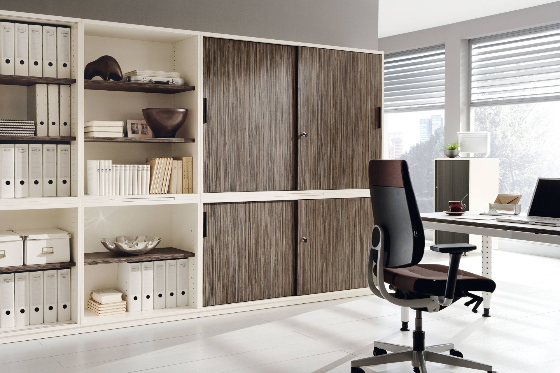 Büro mit Palmberg Schiebetürenschrank, Modell Prisma 2, mit Regalen und Büromöbeln.