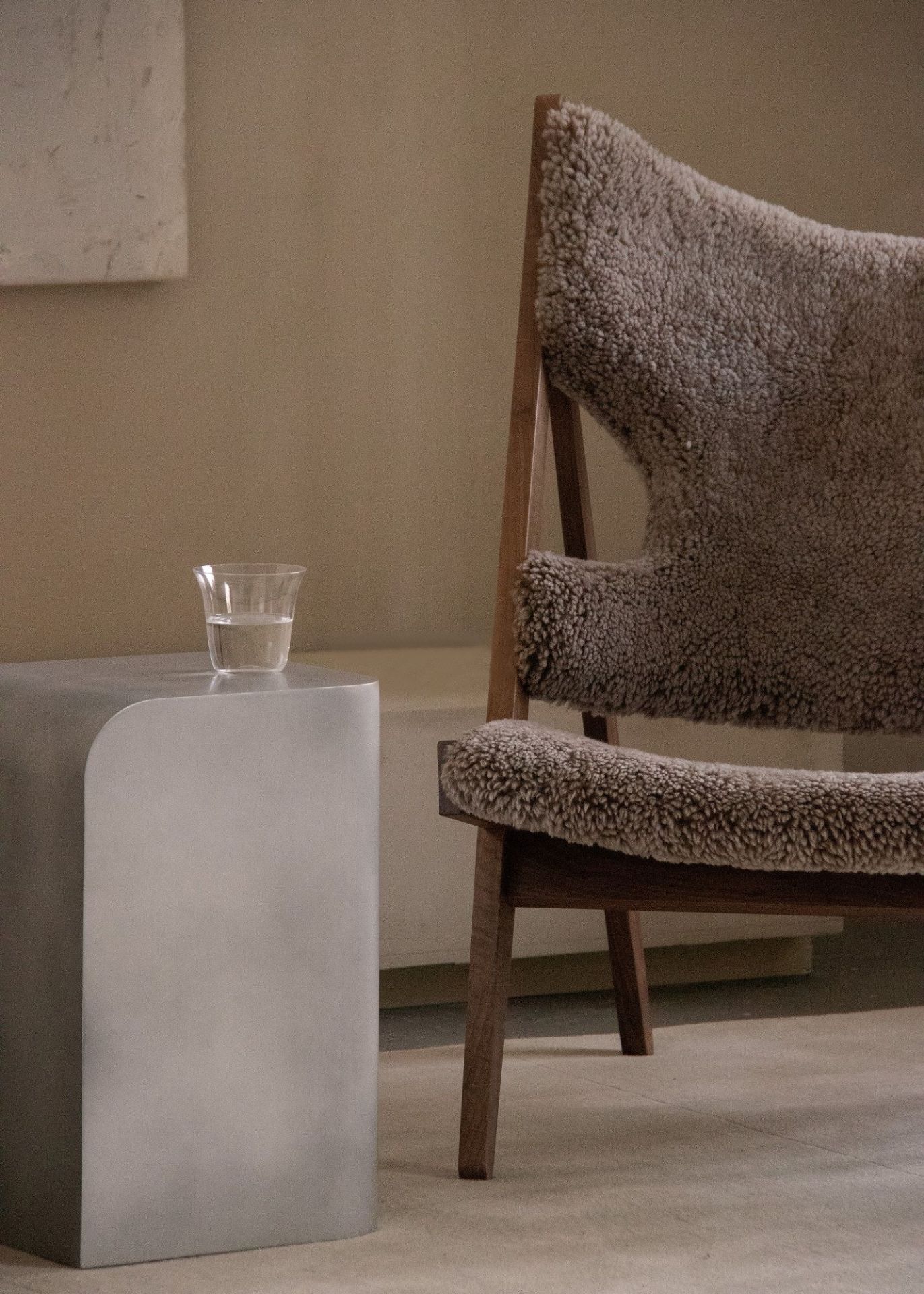 Audo Copenhagen Volume Side Table Beistelltisch aus Metall mit Wasserglas neben Sessel.