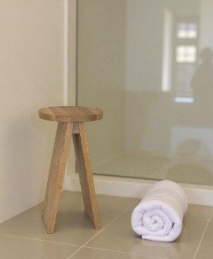 Hocker groß EK02 e15 aus hellem Holz neben gerolltem, weißen Handtuch im Badezimmer. Moderner, minimalistischer Hocker.