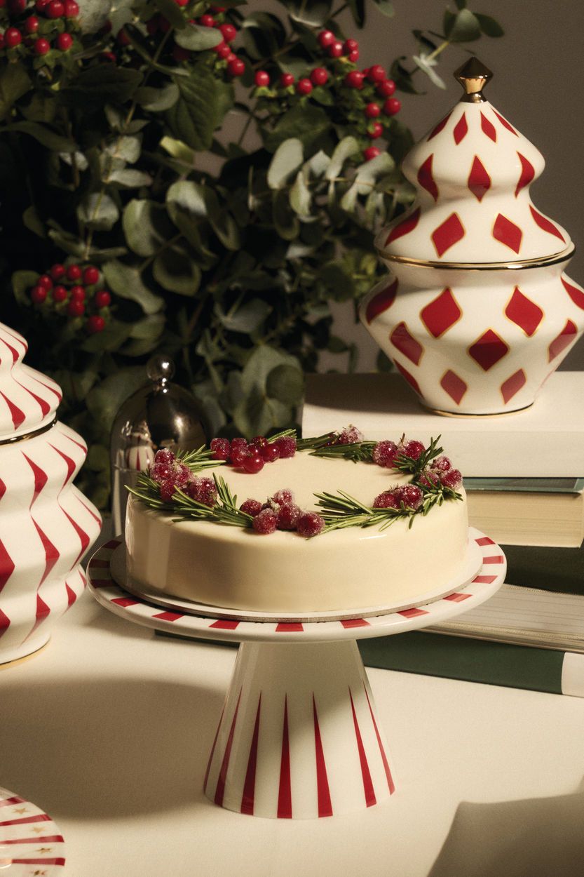 Alessi Delight Etagere aus Porzellan mit Torte, festlich dekoriert, und passenden Vorratsdosen im Weihnachtsdesign.