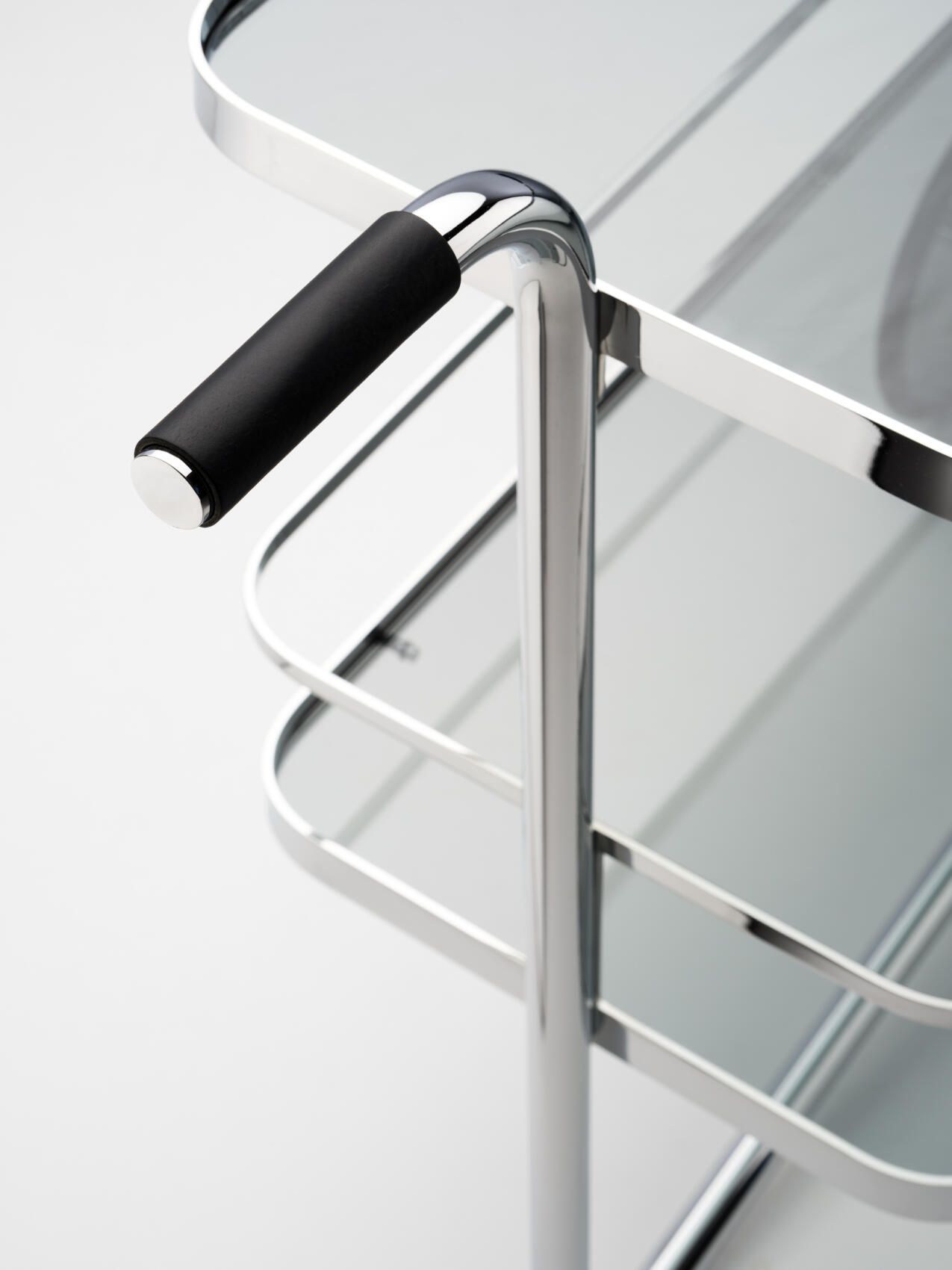 Detailaufnahme des Thonet S 179 Barwagens mit verchromtem Stahlrohrgestell und Glasablagen, Fokus auf Griff.