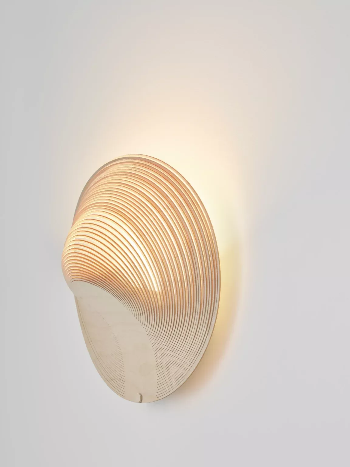 Illan Wandleuchte von Luceplan: Moderne Designleuchte aus Holz, die warmes Licht an die Wand wirft.
