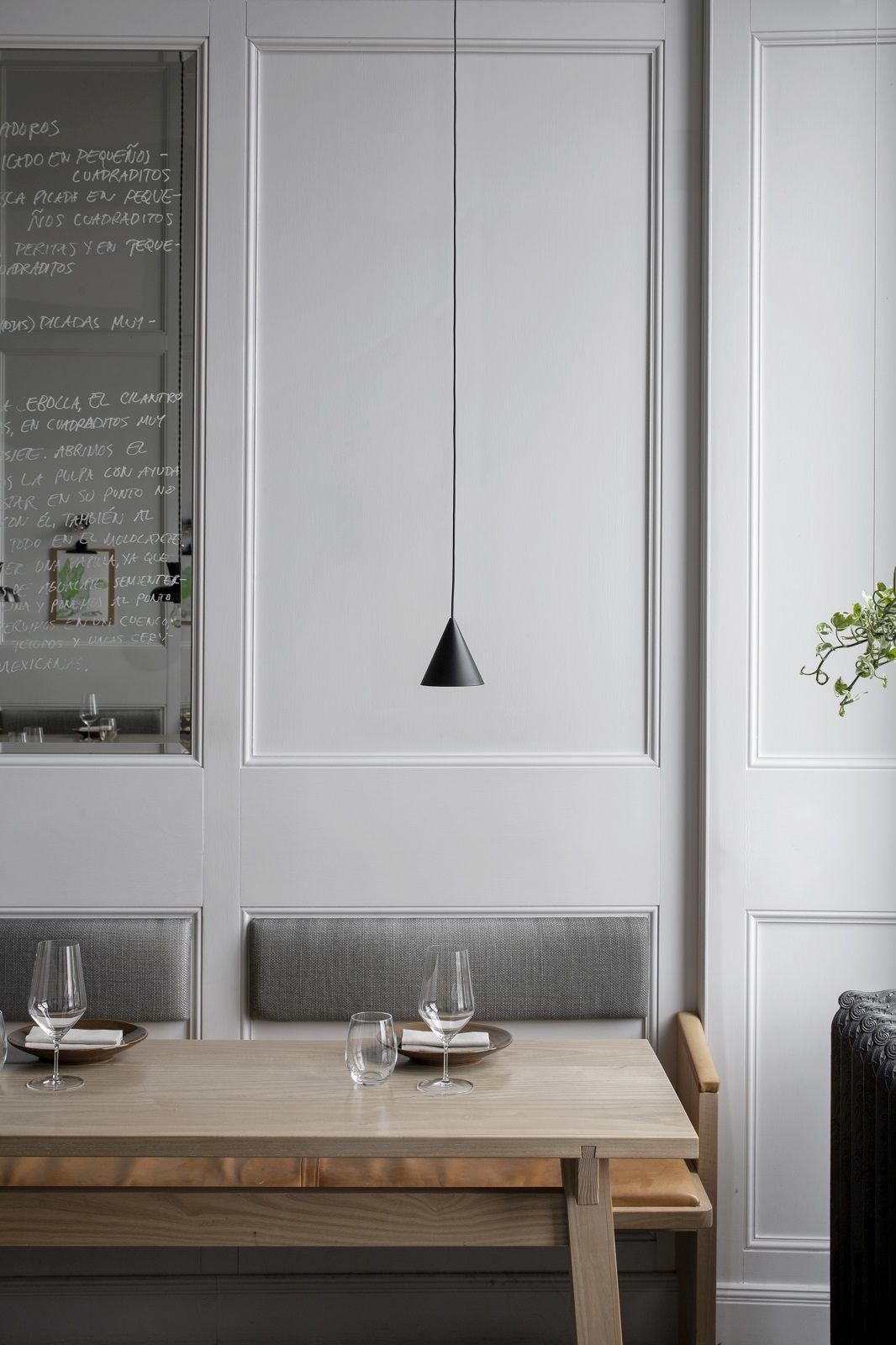 Schwarze w201 S2 Pendelleuchte von wästberg über Esstisch mit Gläsern und Geschirr in modernem Restaurant.