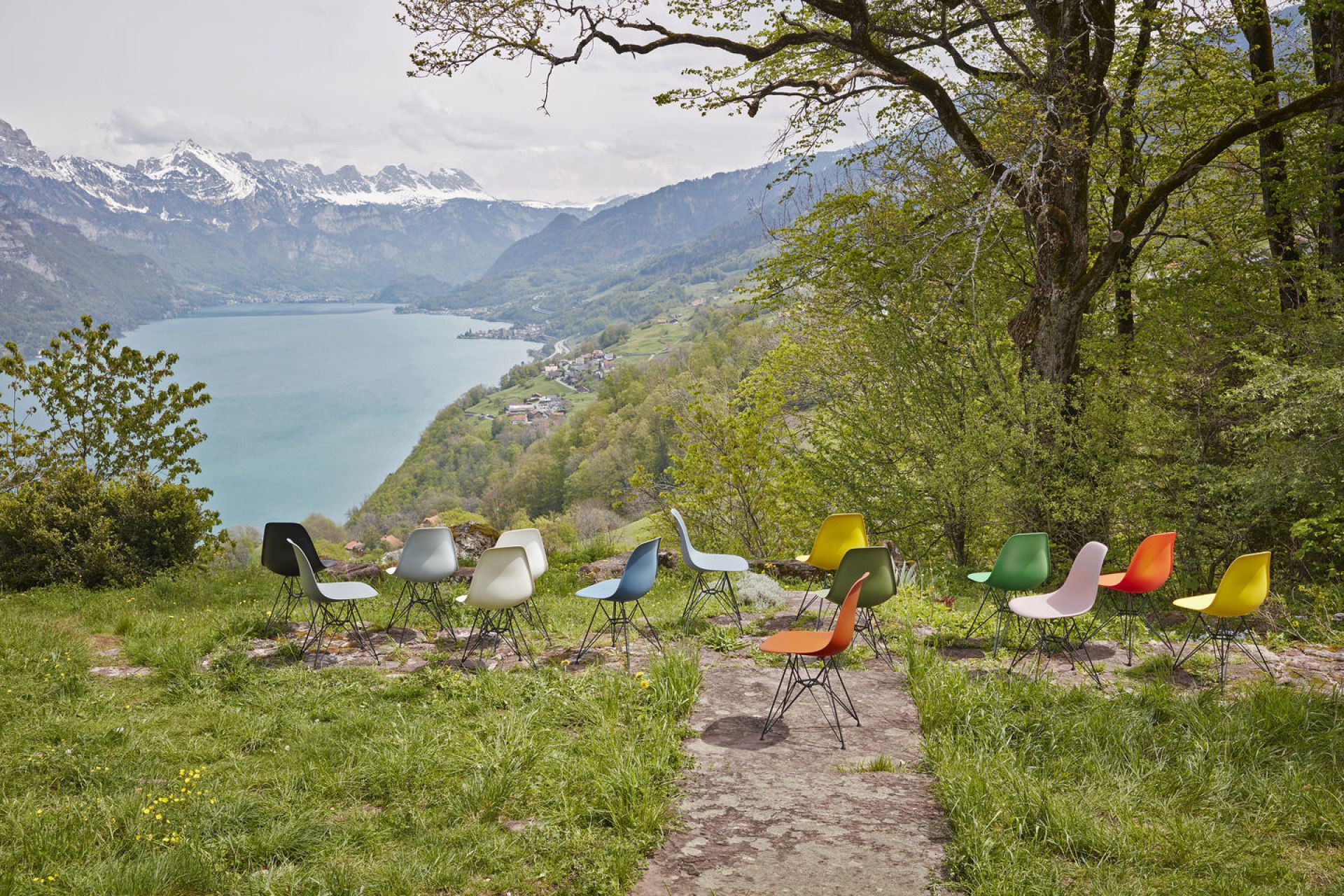 Eames Plastic Arm Chair DAR Stuhl Vitra Verchromt in Kieselstein und anderen Farben vor Bergpanorama.