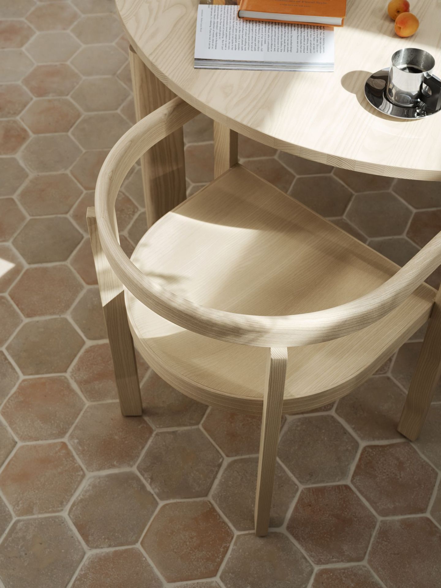 Detailaufnahme des Fritz Hansen After Dinning Esstisches mit Stuhl aus hellem Holz auf Terrakottafliesen.