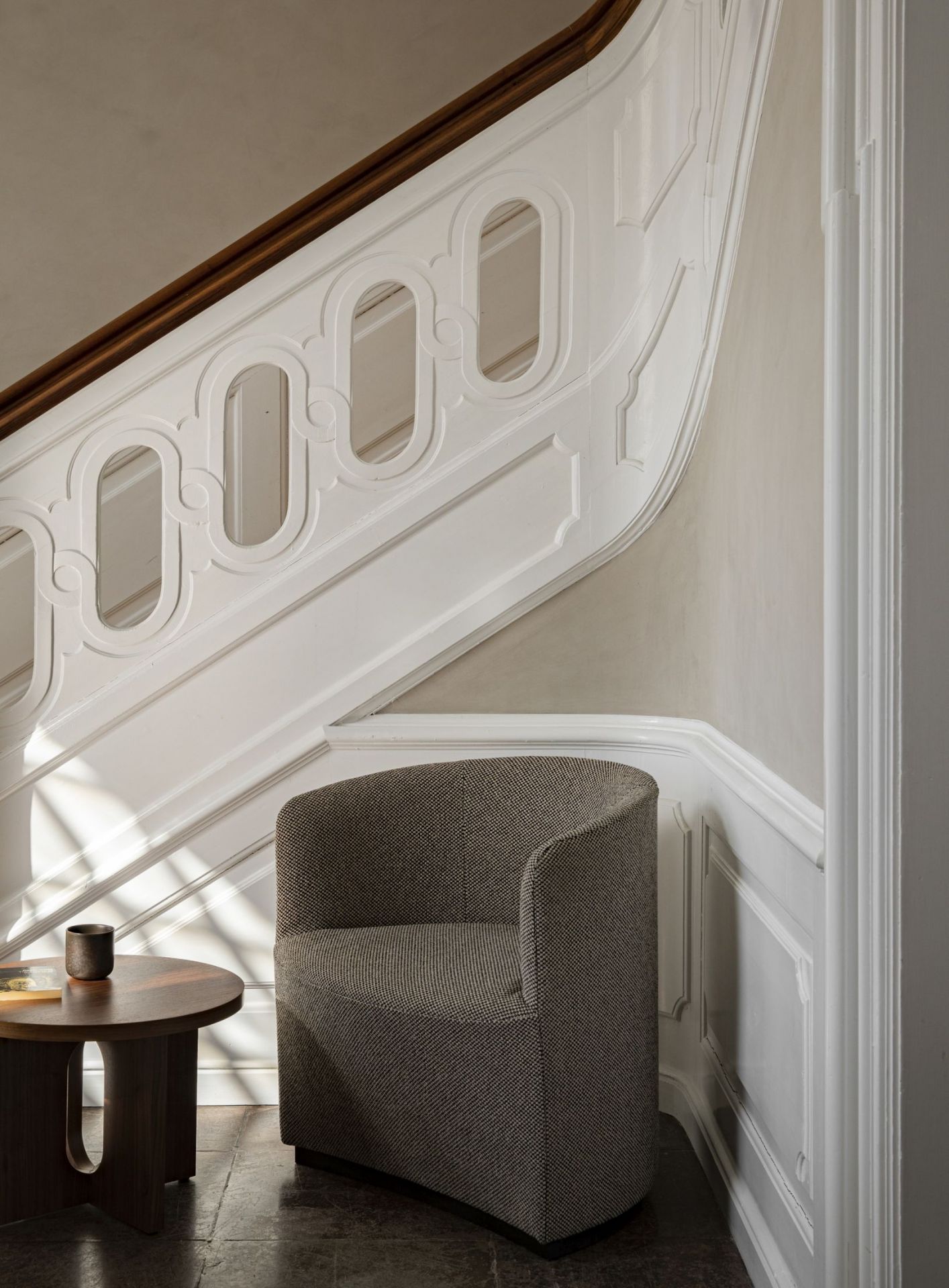 Androgyne Beistelltisch von Audo neben Sessel und Treppe, modernes skandinavisches Design für Wohnzimmer.