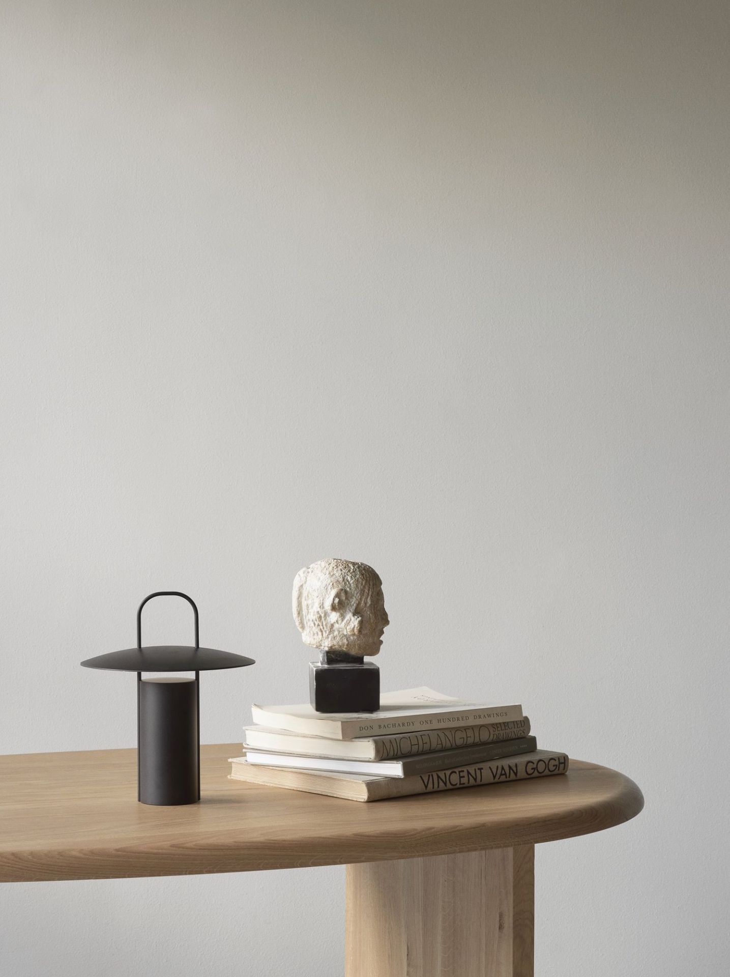 The Eclipse Desk Schreibtisch von Audo Copenhagen auf einem Holztisch mit Büchern und Skulptur.