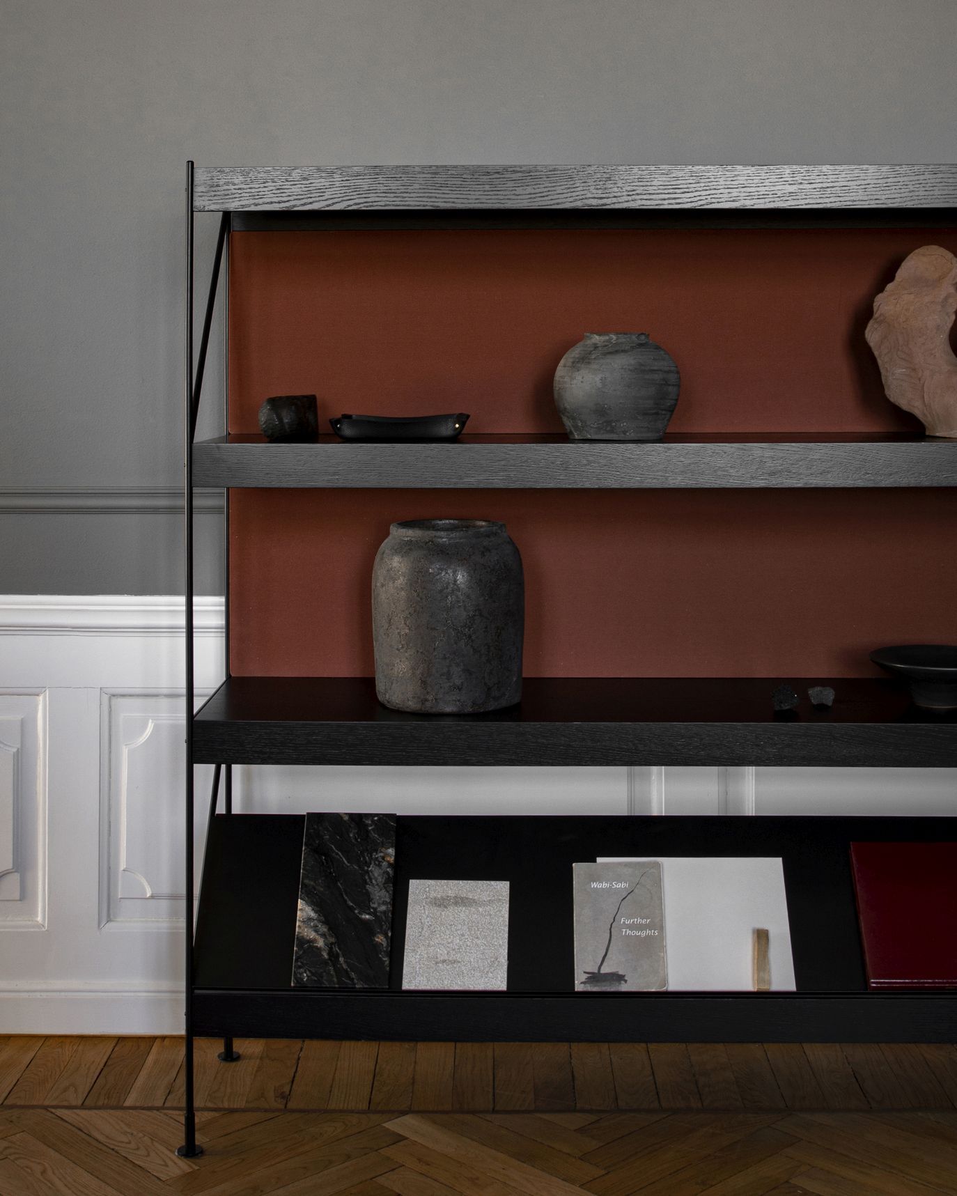 Zet Storage System Regal von Audo Copenhagen mit Deko-Objekten auf dunklen Regalböden.