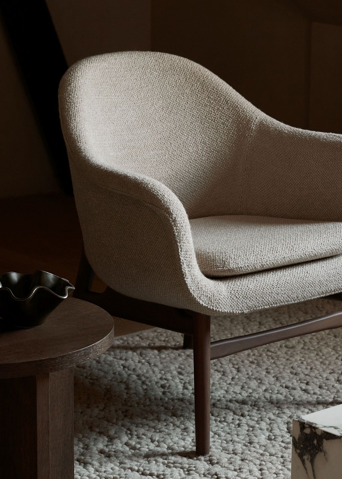Detailaufnahme des Audo Copenhagen Sessels auf einem Gravel Rug Teppich, moderne Wohnzimmergestaltung.