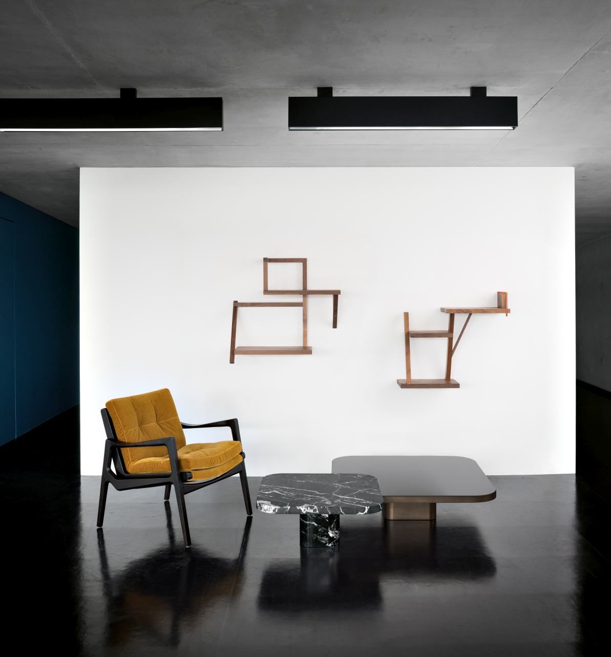 Minimalistisches Wohnzimmer mit ClassiCon Bow Coffee Table, Sessel und Wandregalen vor weißer Wand.