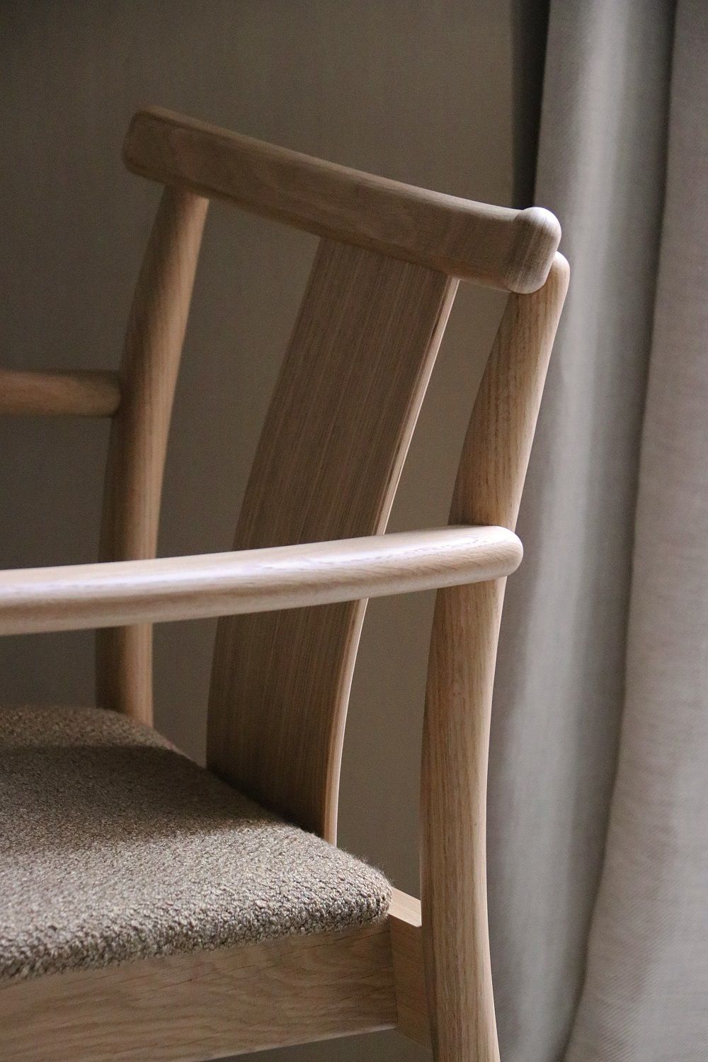 Detailaufnahme des Merkur Dining Chair Stuhls von Audo Copenhagen mit Armlehnen und bequemer Sitzfläche.