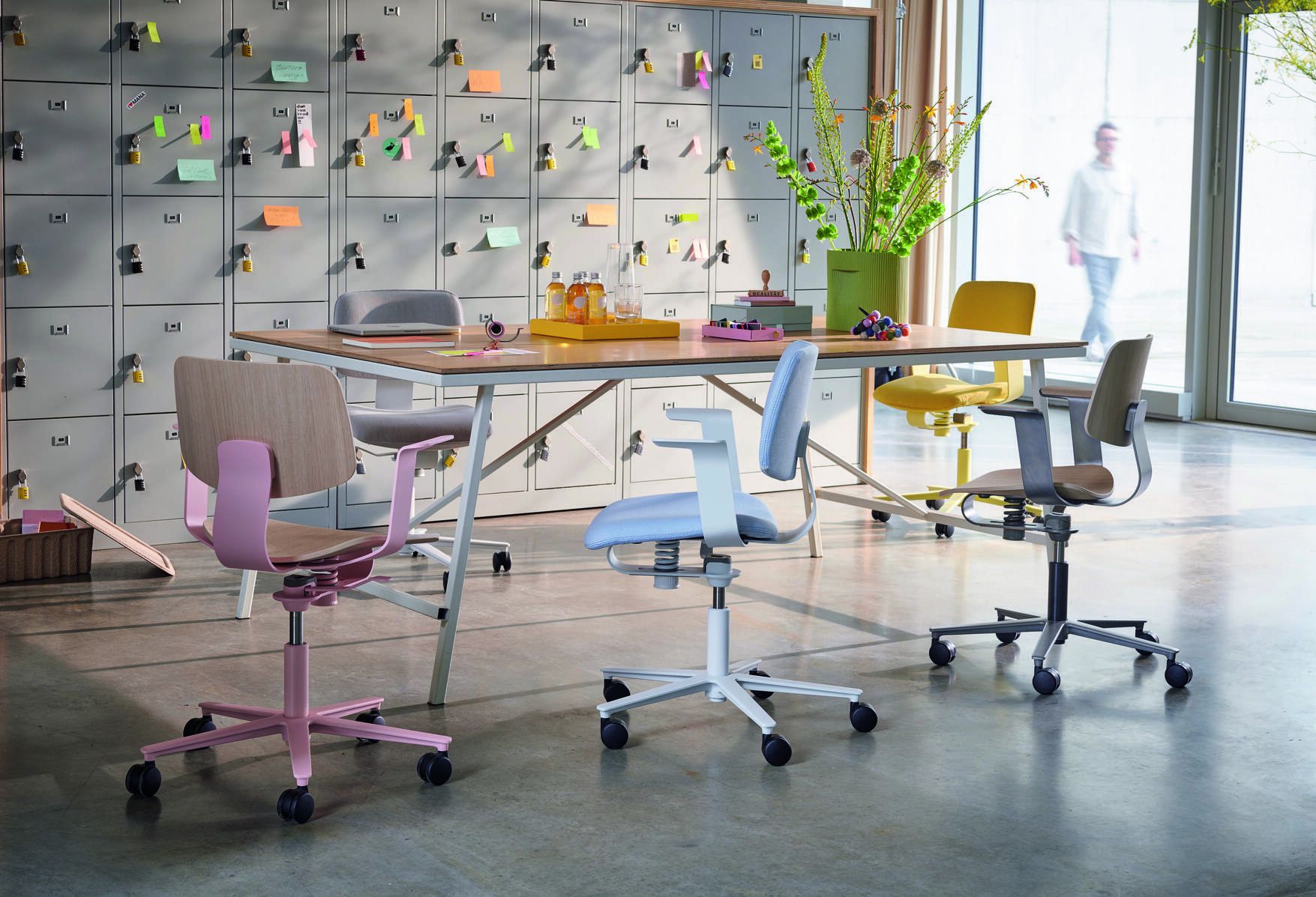 Mehrere 228 WiChair Drehstühle von Wilkhahn in verschiedenen Farben um einen Tisch in einem modernen Büro.