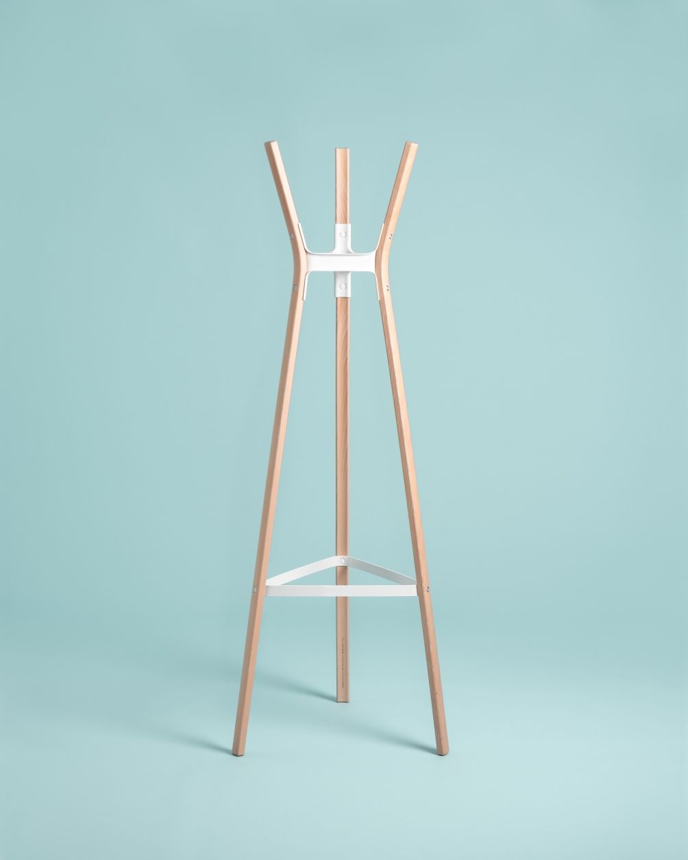 Steelwood Coat Stand Garderobenständer von Magis, moderne Holzgarderobe mit weißem Metallrahmen vor hellblauem Hintergrund.