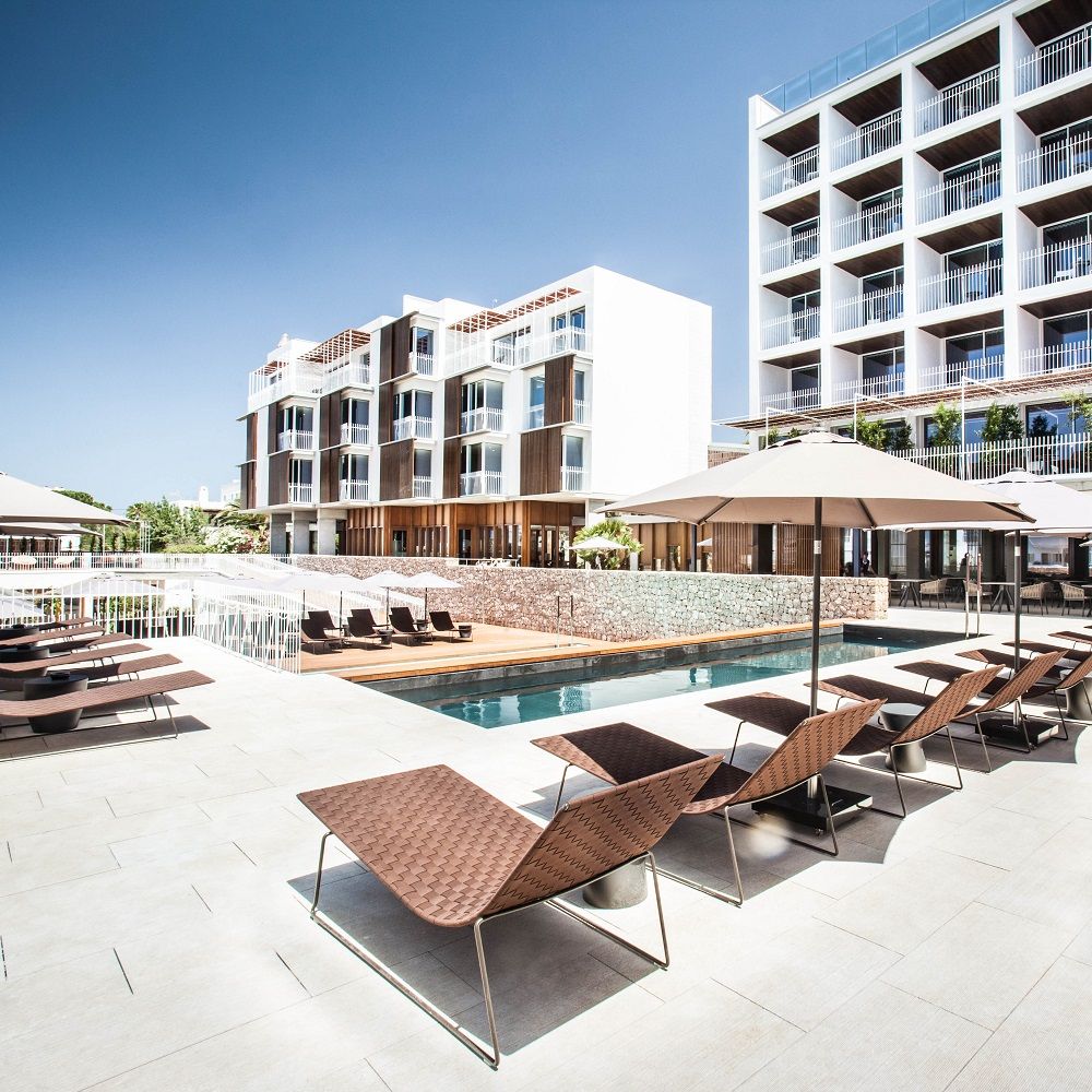 Andreu World Trenza Outdoor Liege am Pool eines Hotels, braune Chaise Lounges mit Sonnenschirmen.