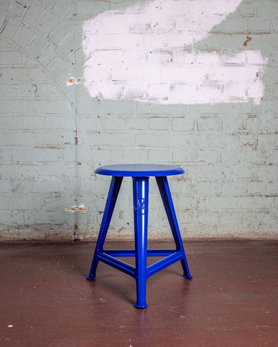 Blauer Rowac Schemel Modell IS, 48 cm hoch, vor einer Wand im Vintage-Look.