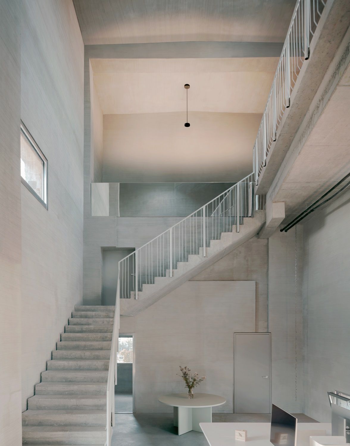 Helle, minimalistische Innenarchitektur mit w224 Alto S1 Pendelleuchte von Wästberg über Treppenhaus und Tisch.
