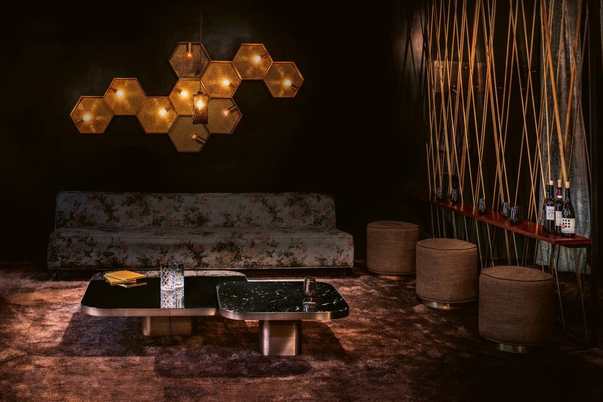 Elegantes Wohnzimmer-Interieur mit ClassiCon Bow Coffee Table, floralem Sofa, Hockern und dekorativer Beleuchtung.