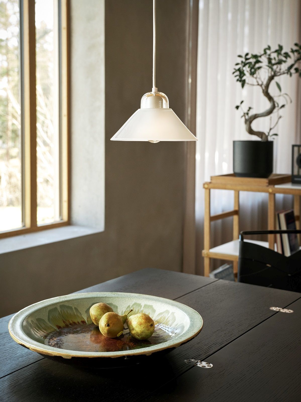 Weiße Kalo Lampe von Design House Stockholm über Esstisch mit Birnen in Schale.