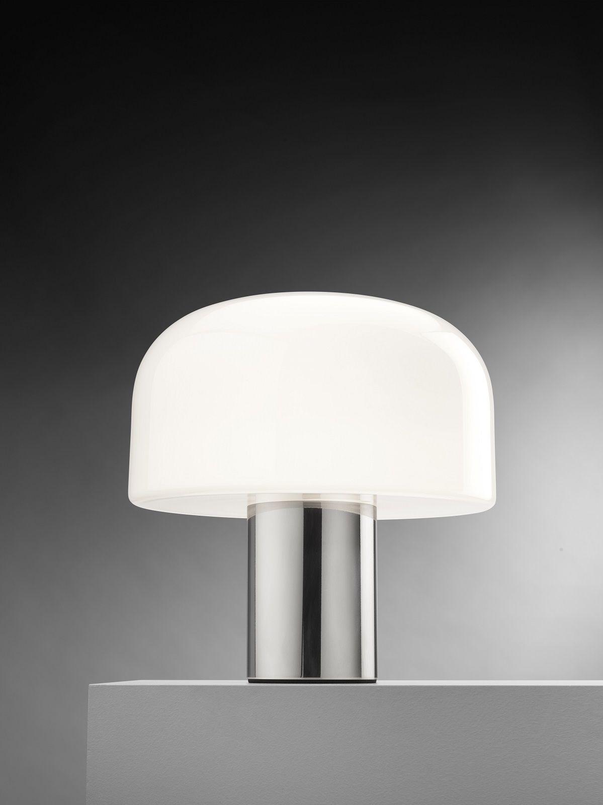 Nahaufnahme der Flos Bellhop Tischleuchte aus Glas mit poliertem Metallsockel und weißem Diffusor.
