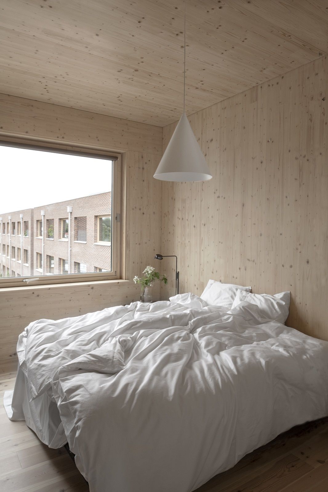 Helles Schlafzimmer mit Bett und w221 S2 Medium Pendelleuchte von wästberg, Kegelförmige Hängelampe über dem Bett.