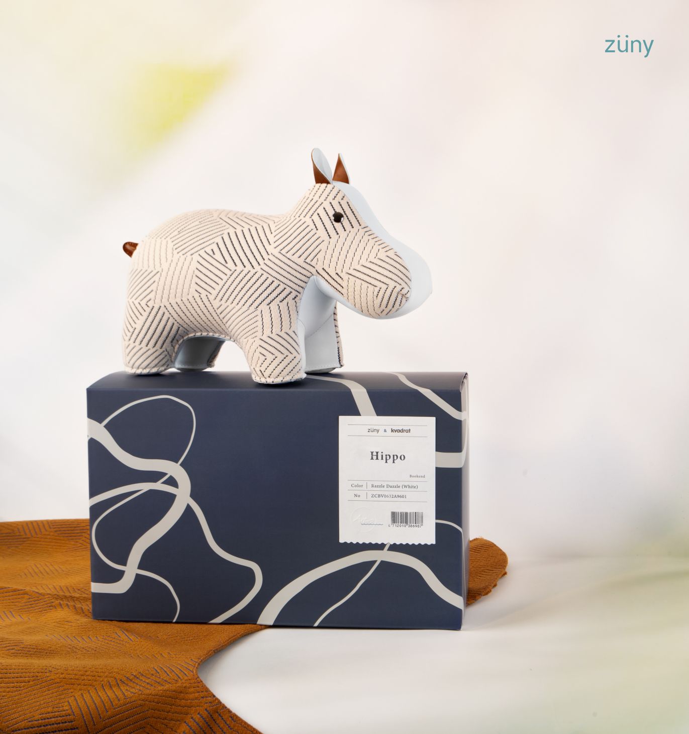 Weiße Hippo Buchstütze "Razzle Dazzle" von Züny x Kvadrat auf einem Geschenkkarton, Dekoration für Kinderzimmer.