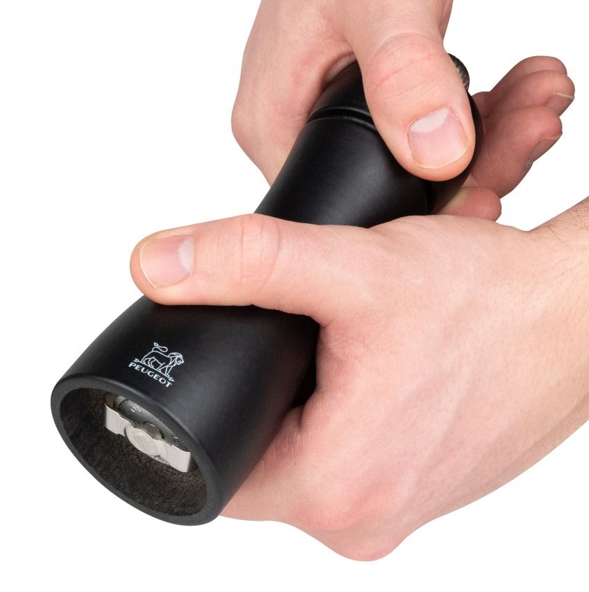 Nahaufnahme: Hände bedienen schwarze Peugeot Tahiti Mühle, ideal für Salz und Pfeffer.