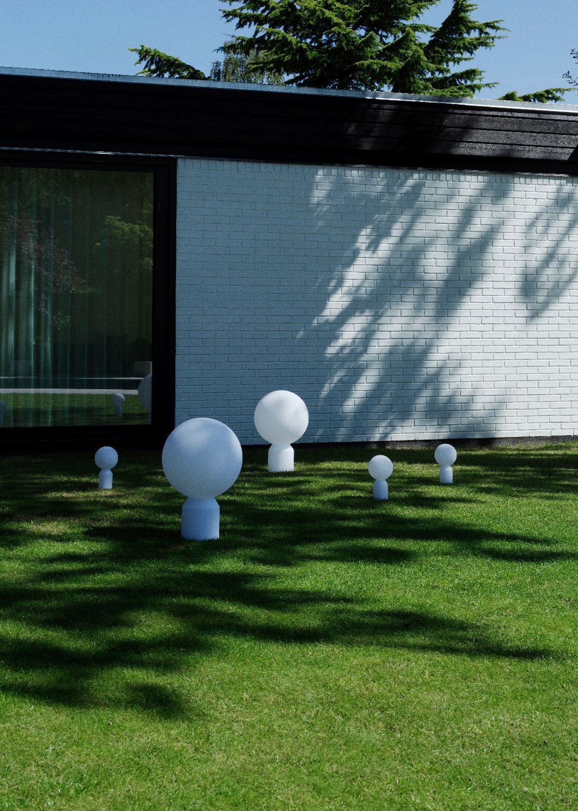 Mehrere Yo Lamp Small Akkuleuchten von Normann Copenhagen auf Rasen vor einem modernen Haus.